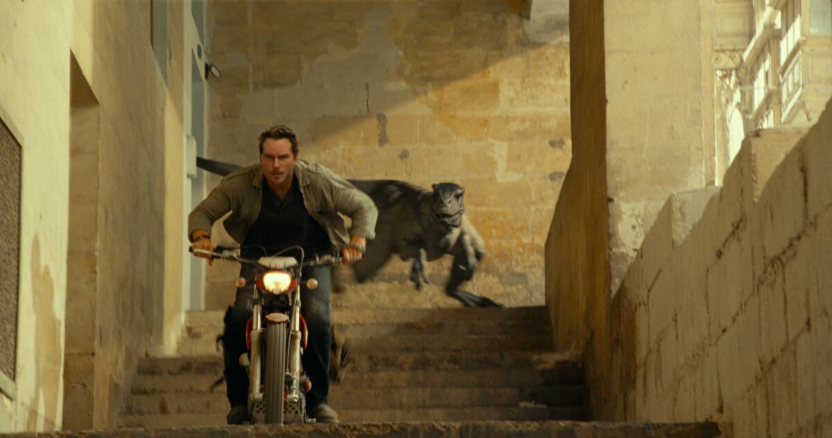 chris pratt on a motocycle racing away from an atrociraptor